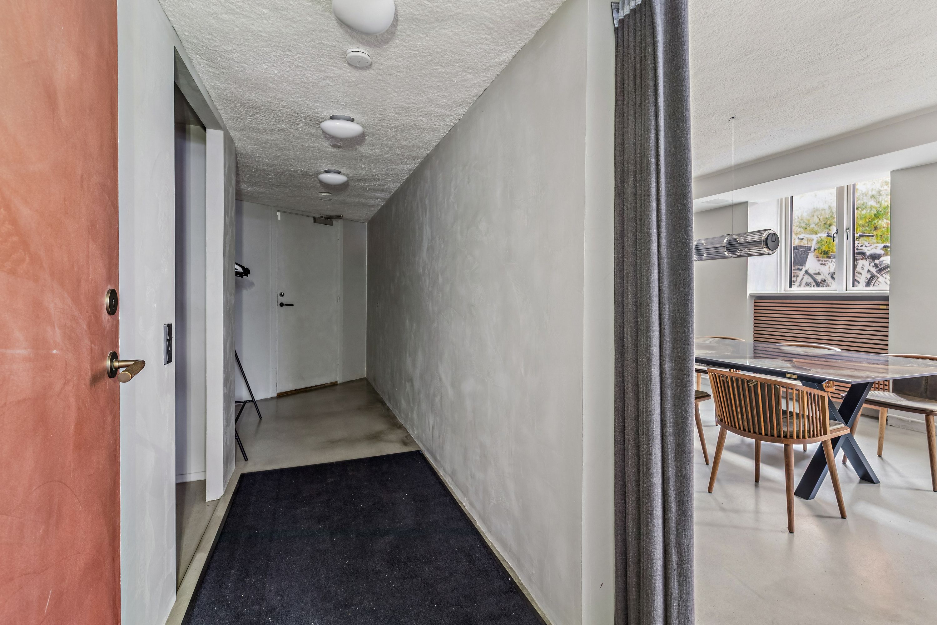 Et moderne interiør med hvide vægge, en træbord og sæder samt et lysekron lys i loftet