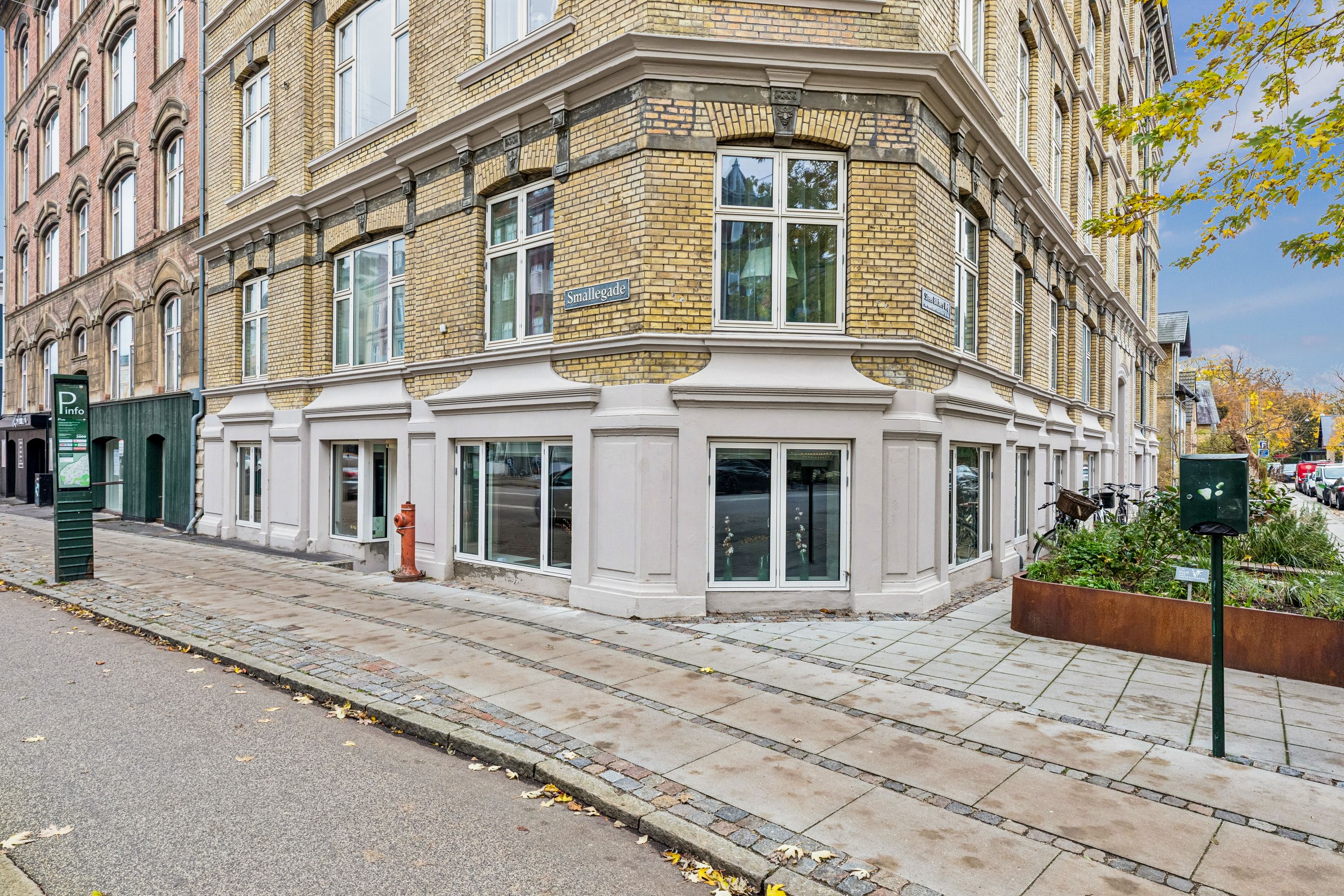 En lejlighed med butikslokaler på Smallegade i Frederiksberg med fire vinduer og rødt brandslå udenfor