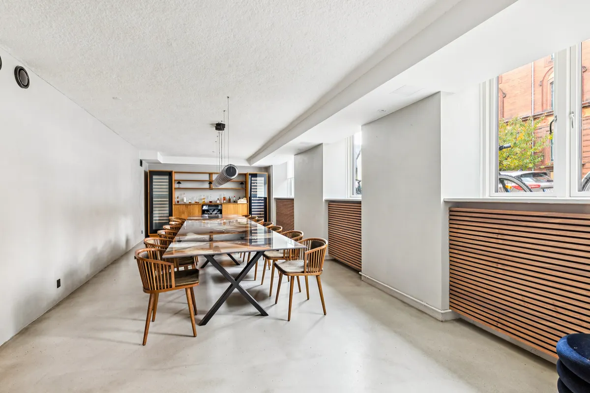 Lejlighed med elegant glasbord og stole i en moderne stue med hvide vægge og lyse gulv