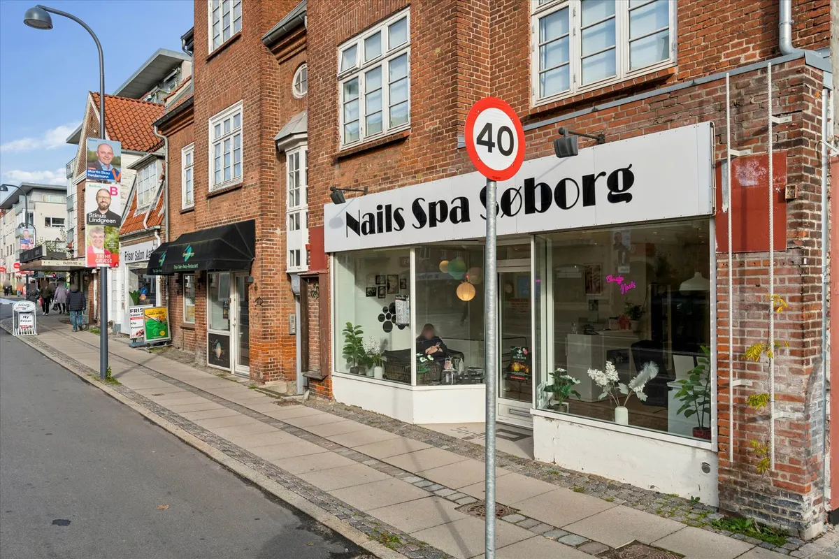 Butik med navnet Nails Spa Søborg. Butikken har glasvinduer med lyse buer og mange dekorationer. Der er et skilt med