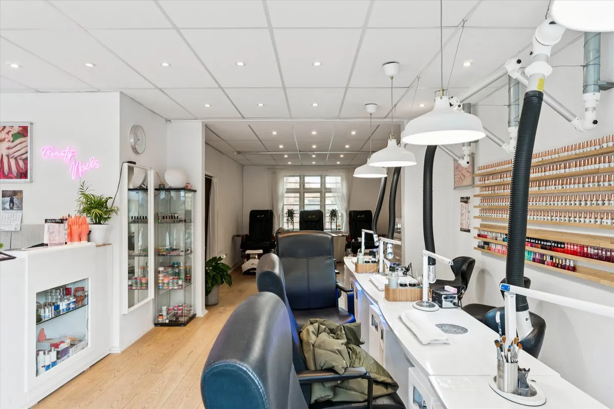 En moderne og pæn indretning med høje lofter, lyse gulve og lysekroner med hvide lampeskærme. Der er stolpeformet