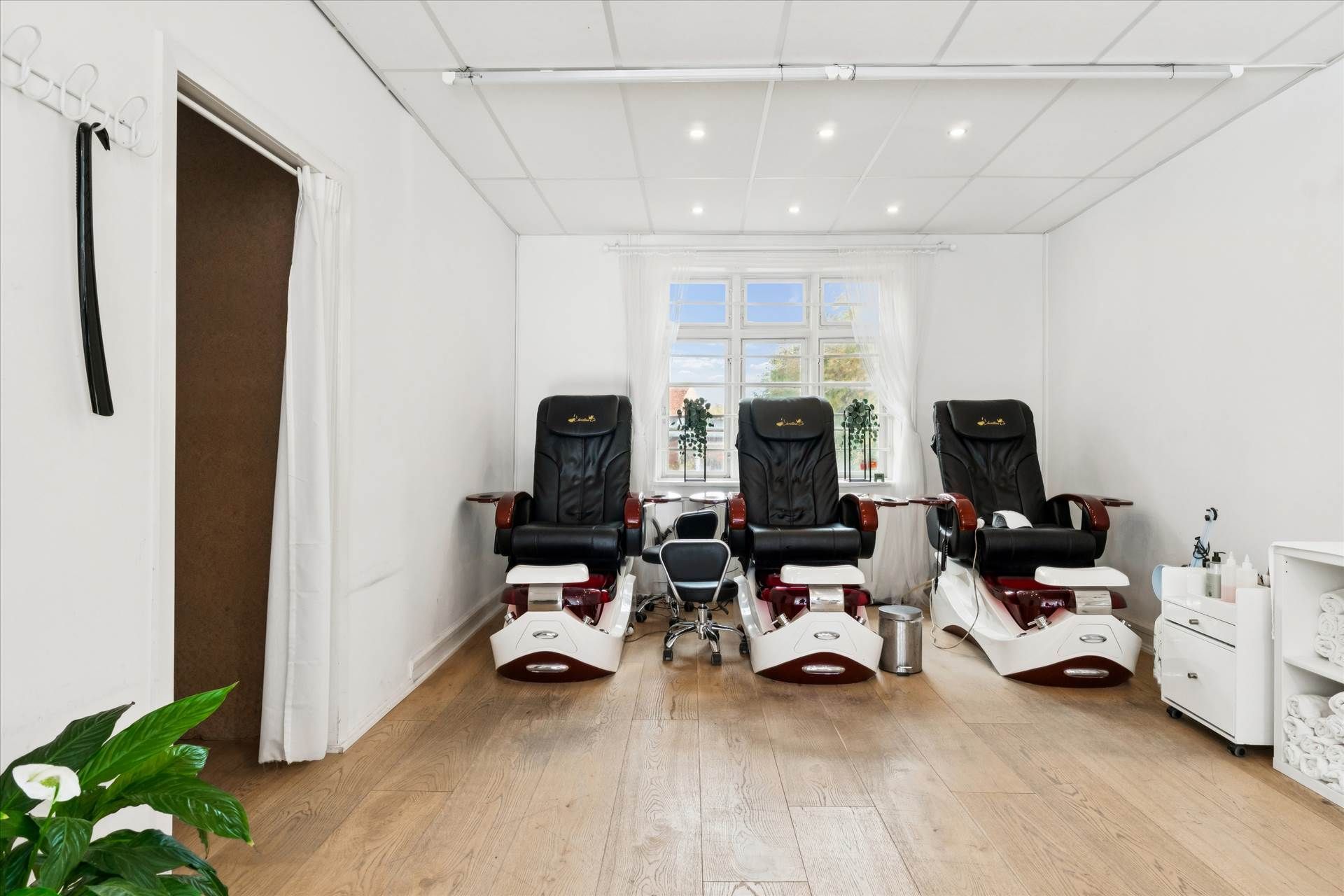 Inde i en veludstyret salon er der tre moderne spa-stole og en sidebord med flere produkter til kosmetiske behandlinger