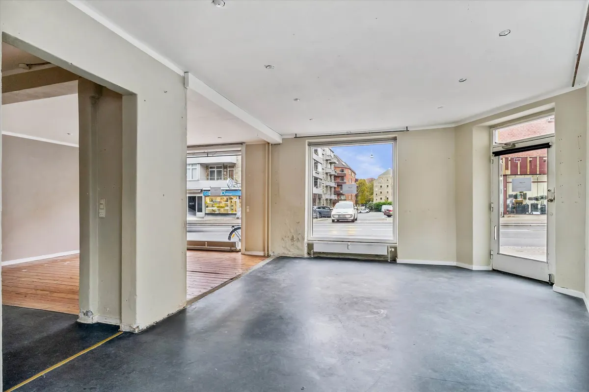 Lokaler med glasruder og hvide vægge samt parketgulv og svartgulv indvendigt og udsat til gaden