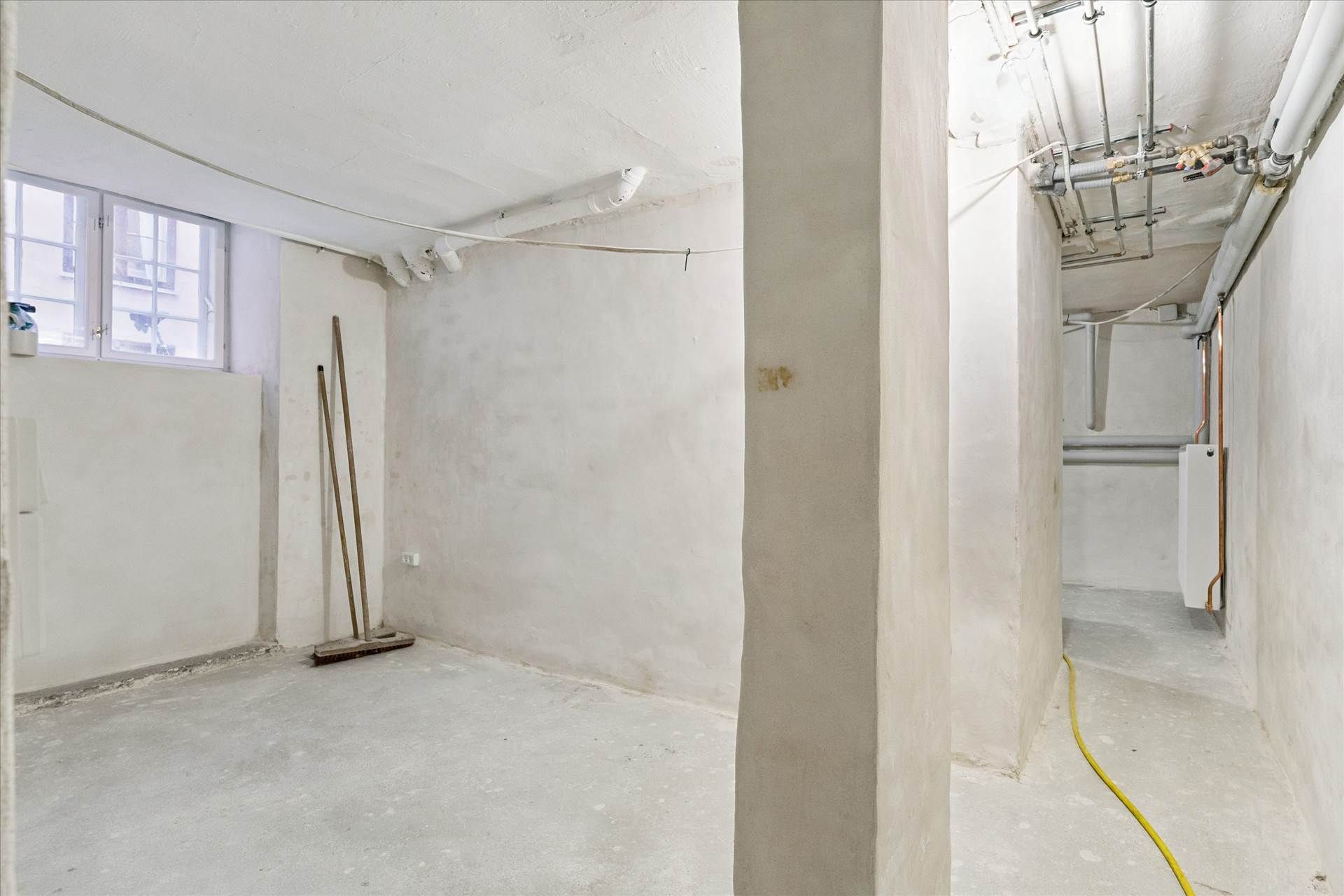 En stor og velholdt fredet ejendom, der er direkte overfor Kongens Have, med et ubenyttet rum med lysegrå vægge, gulv og