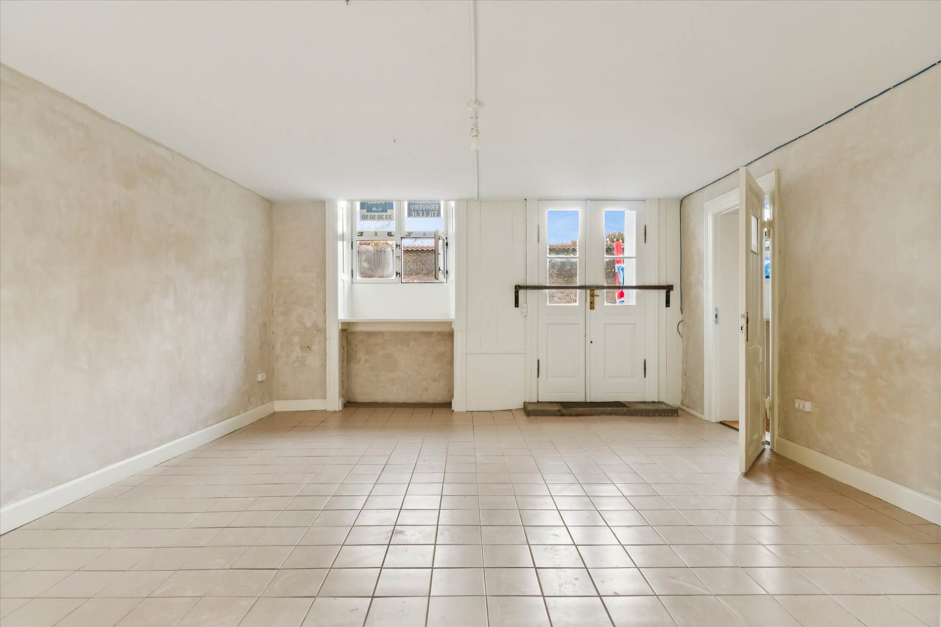 Tomt og rummeligt lokale med højt loft og lyse gulvfliser og hvide vægge i nyrenoveret bygning over Kongens Have