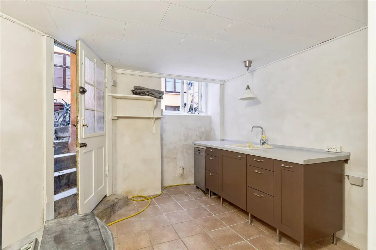 En stor køkkenkomfur med vandhaner og skarpe kanter samt en lysarm og en åben dør med stiger til en gårdhave