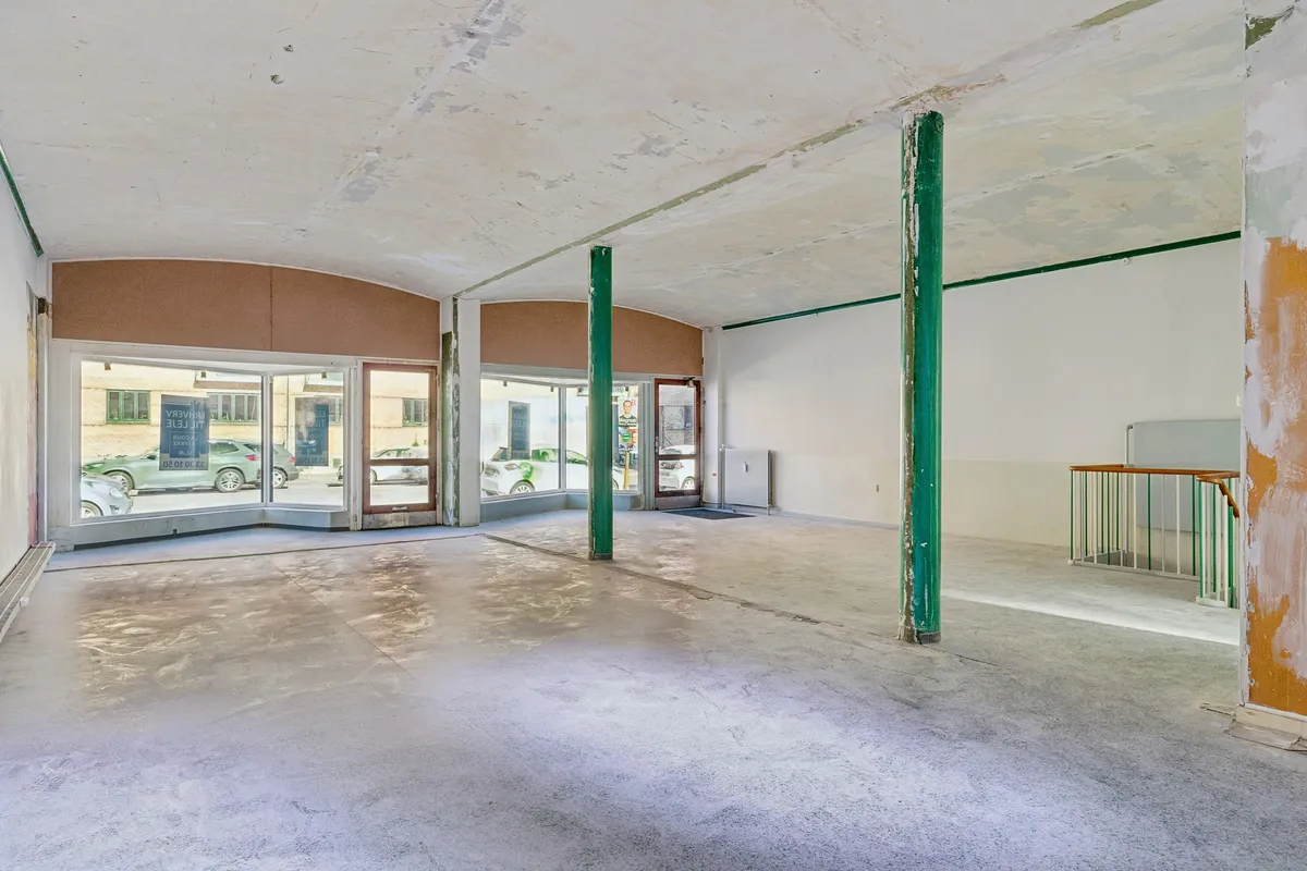 Ledig lejlighed på 104 kvm med store vinduer og indgange, to grønne støtter og lysegulv, 77 kvm kælder og garage.