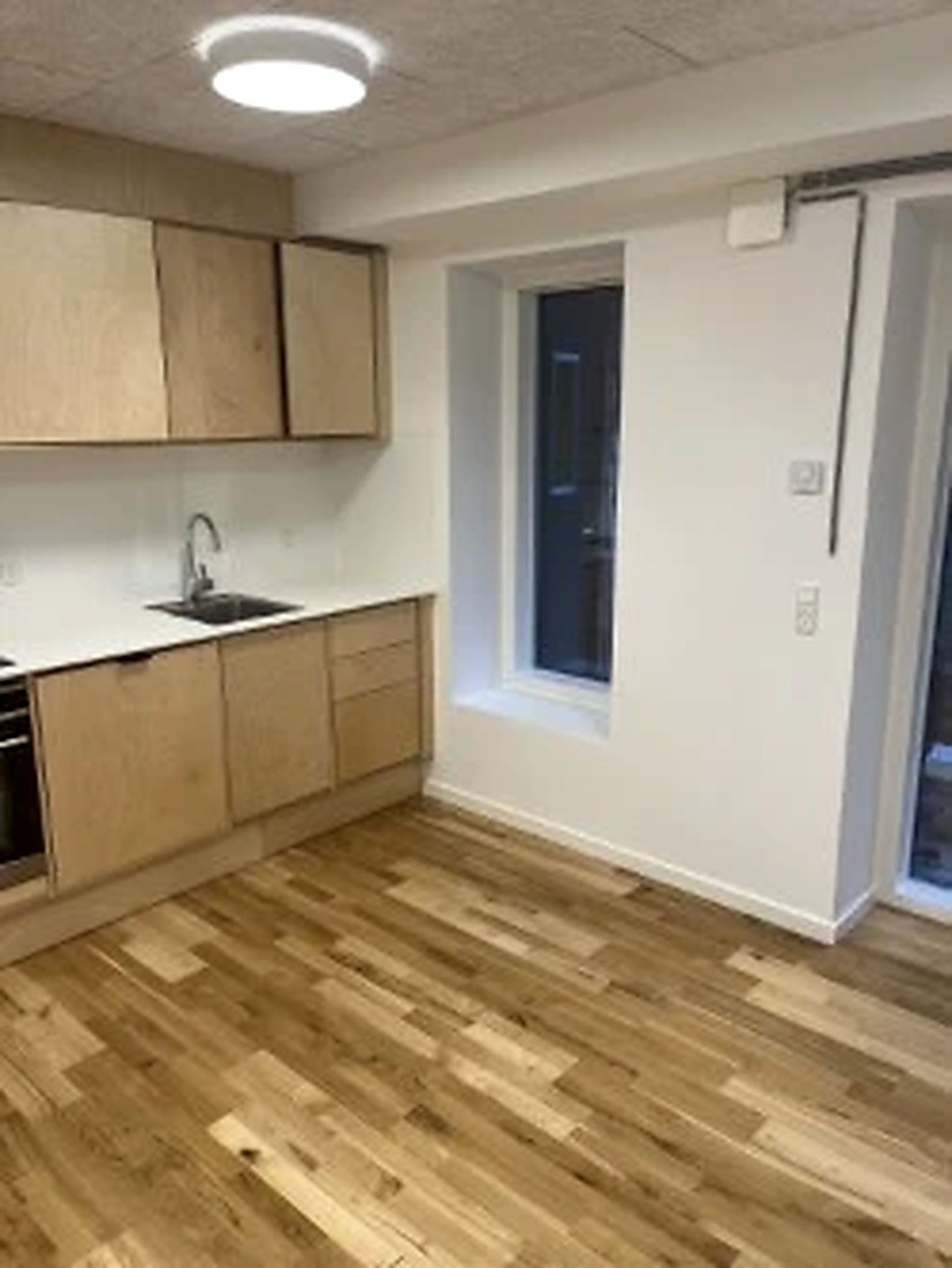 Kontorlokale med eget køkken og badrum. Rent og pænt køkken med lyse træskabe, hvidt arbejdstræk og gulvbelægning. Vindue med glas og træindfatning.