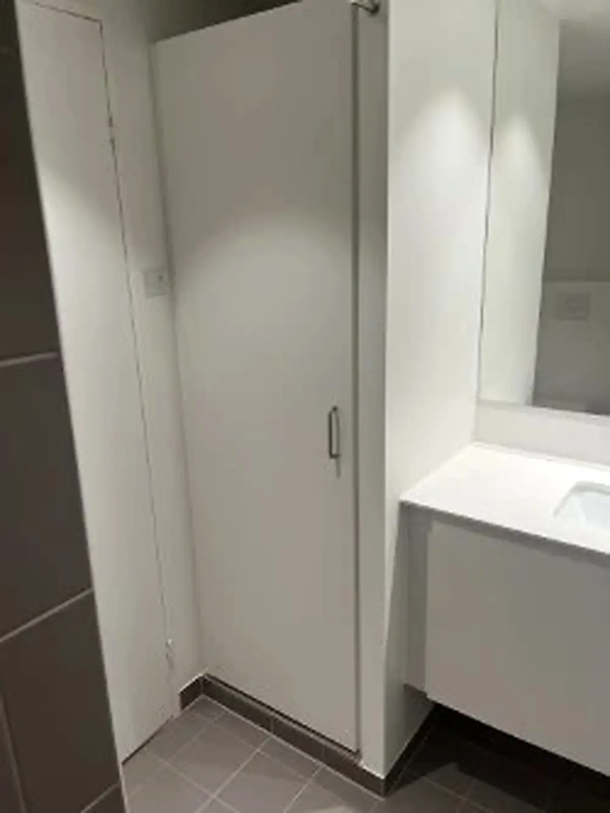 Rent kontor med hvidt badeværelse og stort spejl. Værelset har højtloft og højkvalitetsgulv.