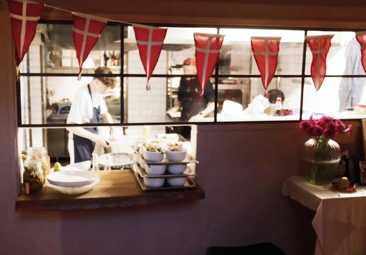 Take-away med selskabslokale til leje på Østerbrogade 64, København Ø. Køkken med rød dansk flagdekoration og to medarbejdere bag vinduet