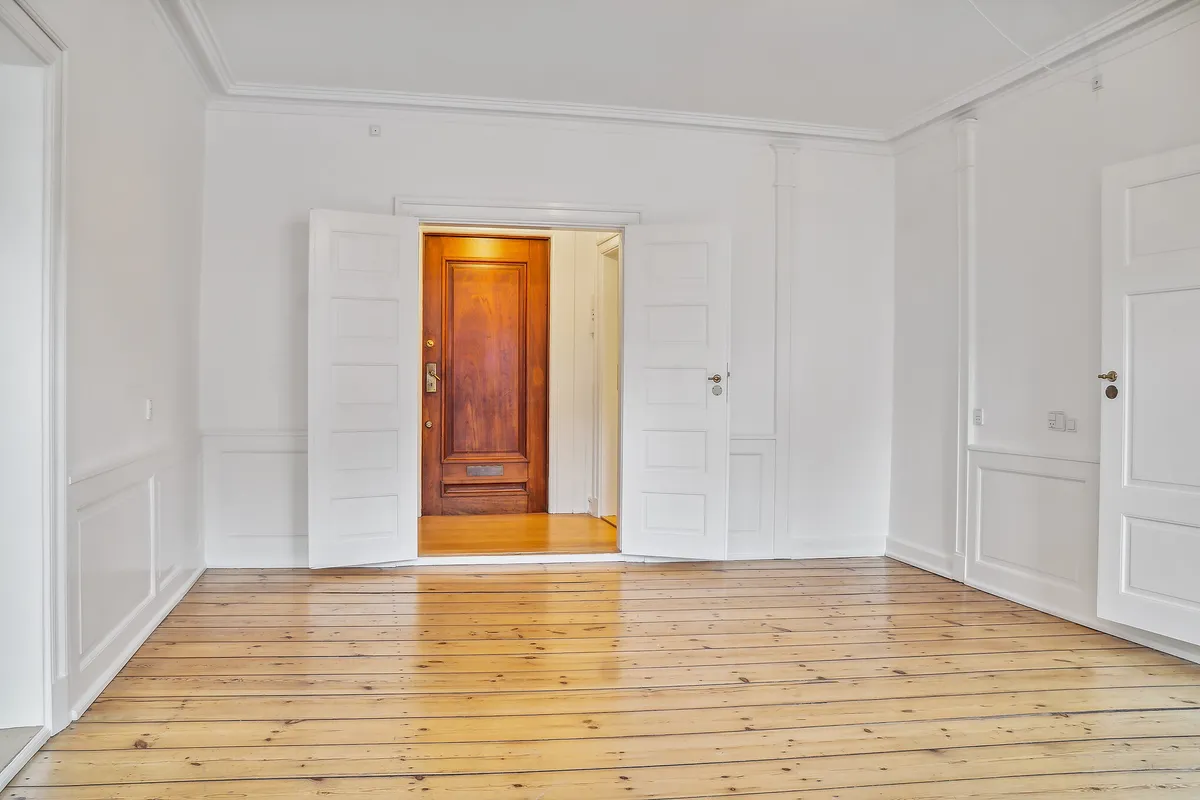 Kontor med åbne hvide døre og trægulve i København. Lyst og velplejet rum med lyse hvide vægge og lyse døre.