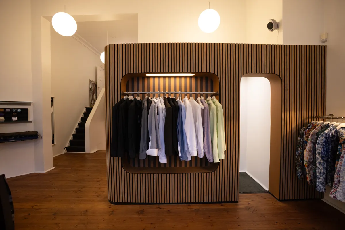 Butik med tøjskabe og strygejern placeret på Frederiksborggade i København. Trægulvet og hvide vægge skaber en hyggelig atmosfære.