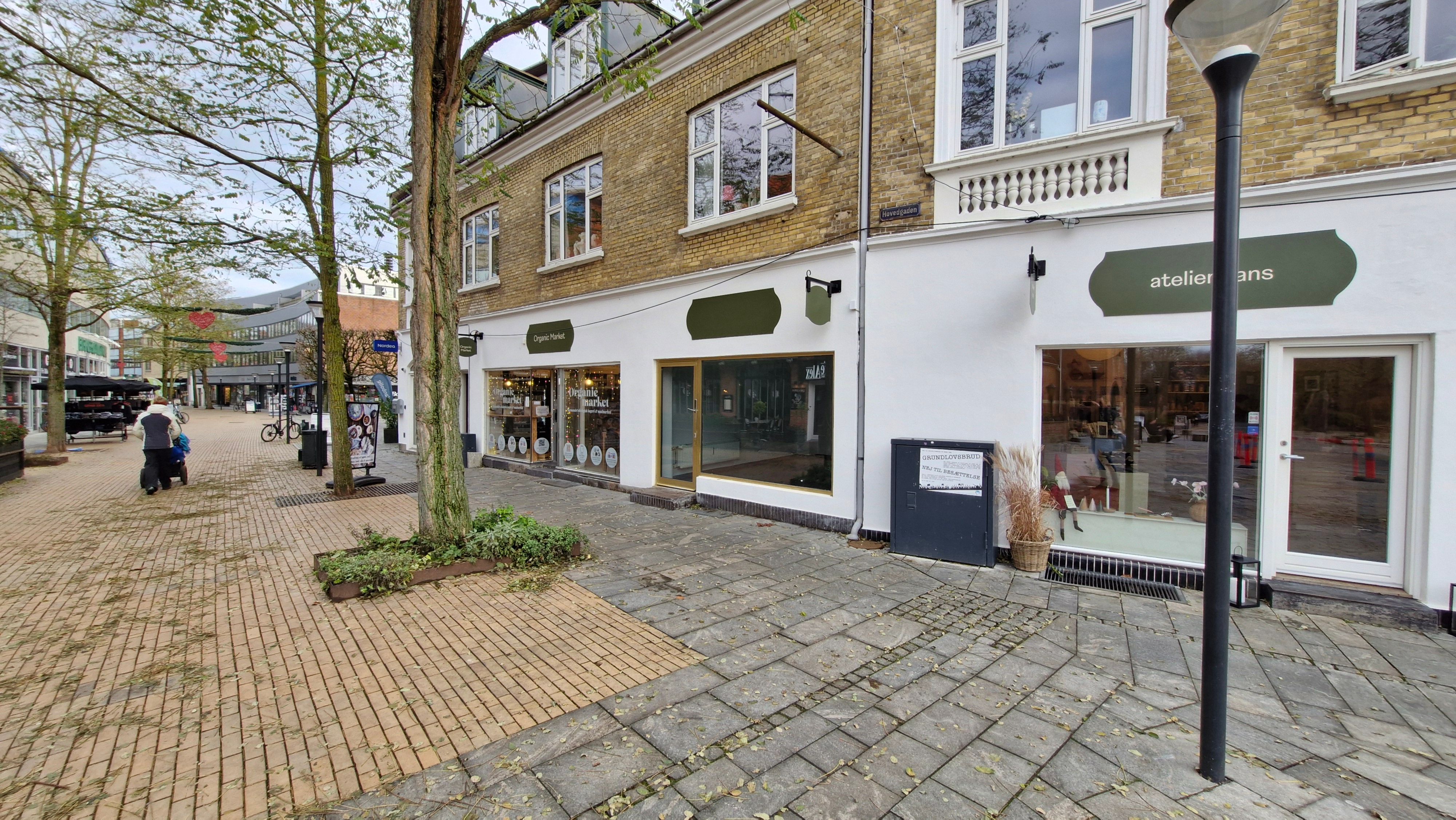 En forretningsforretning med navnet Atelier Mans og Organic Market er lige på hjørnet af en gågade i Birkerød