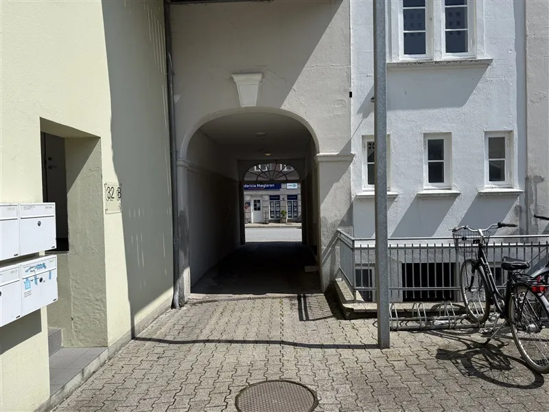 En lille gårdhave med stengulv og to parkerede cykler samt en tøskrave til højre