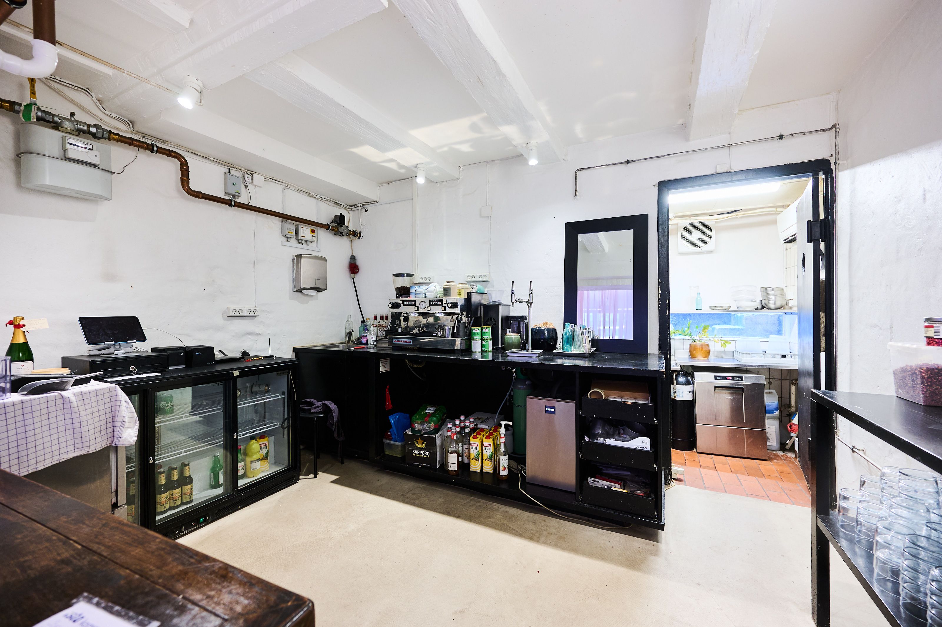 Et moderne køkken med lyse vægge og sort diskompartement og apparater samt et køleskab og en flaske champagne