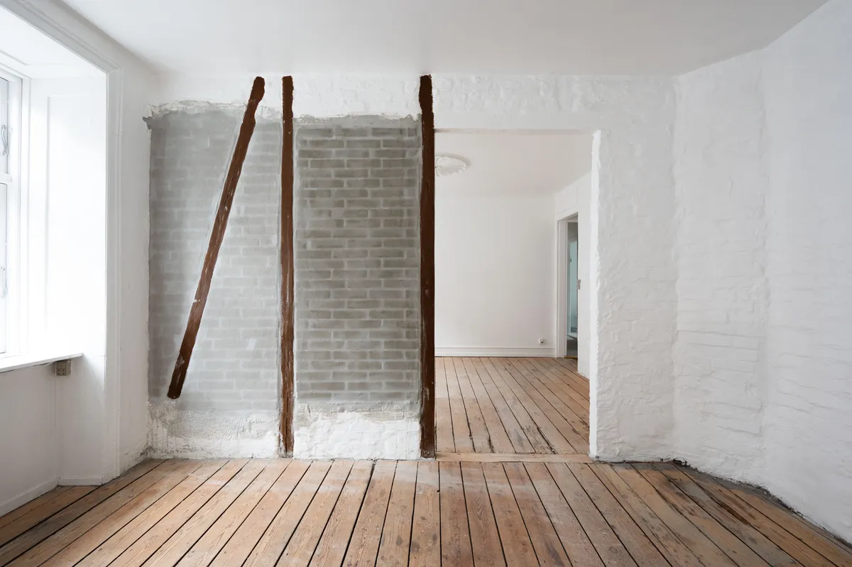 Et værelse med hvide vægge og gulv og en åben dør til et værelse med hvide vægge og et gulv