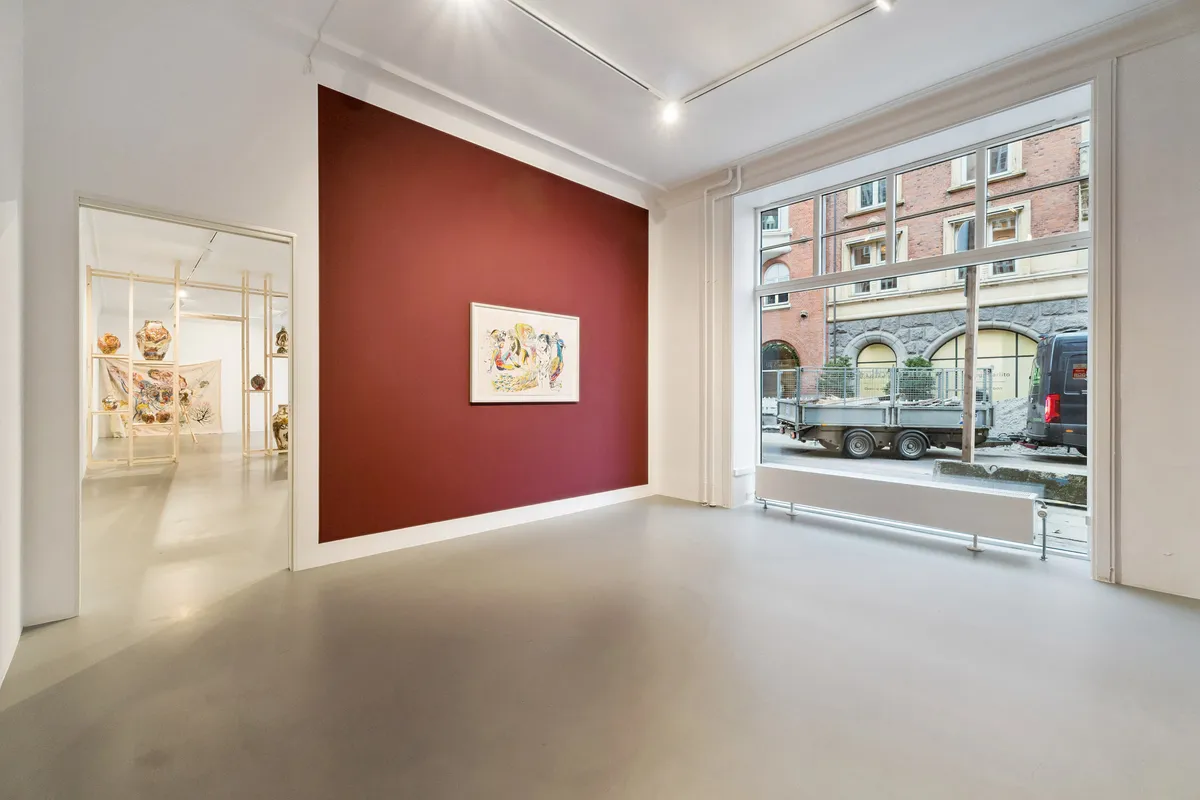 Værelse med hvid og rød væg, gulv, loft, kunstværker, vinduer og døre, og udsigt til gårdsplads med lastbil og bygninger