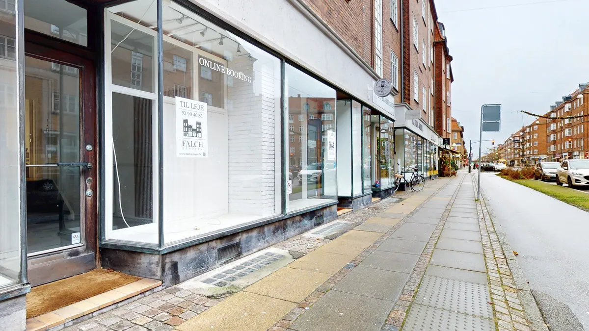Lejlighedsvisning af butik med skiltfalch erhverv, online booking og kontaktoplysninger i Frederiksberg. Butikken ligger på hjørnet og har store ruder med skrift på vindue