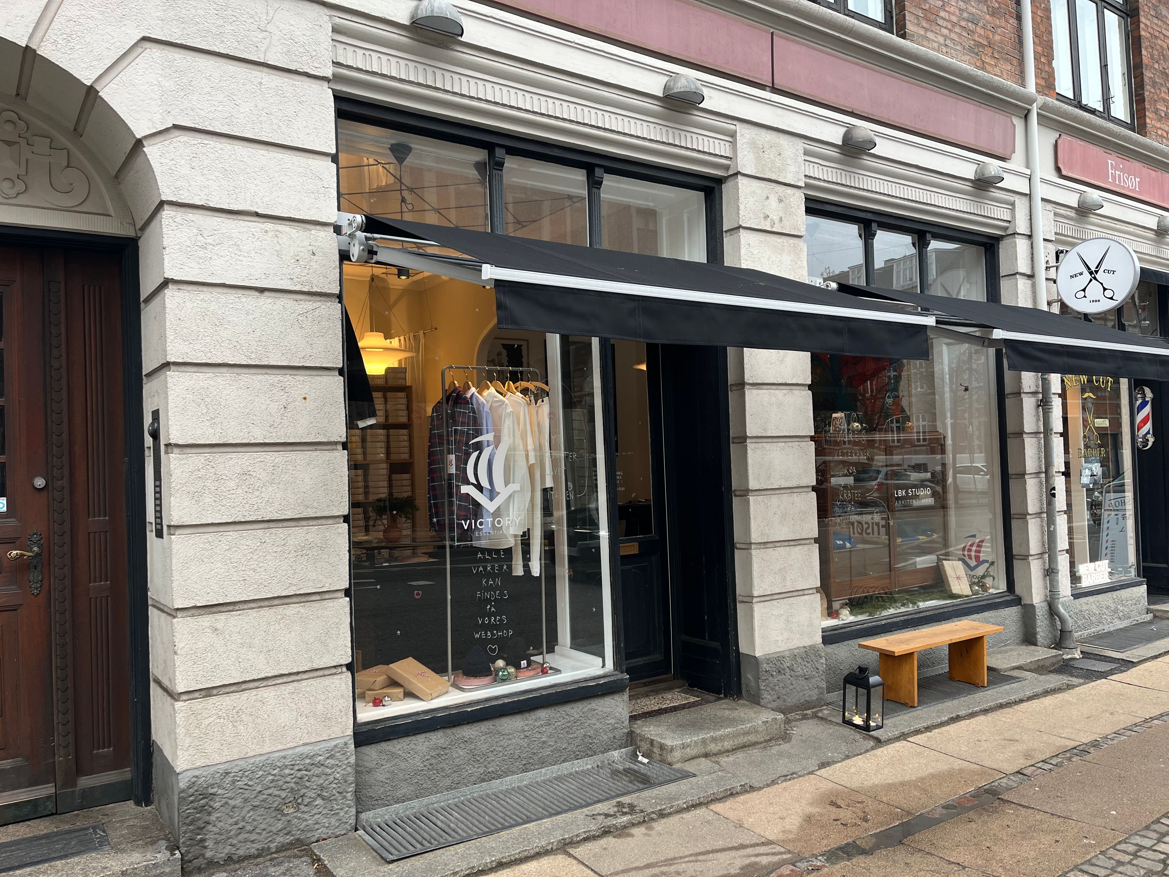 Vesterbrogade 206, Frederiksberg. Flot butikslokale med mærket Victory. Sort markise og lysekroner. Inde er tøj og smykker udstillet. Lys, velplejet og hyggeligt butikslokale til leje.