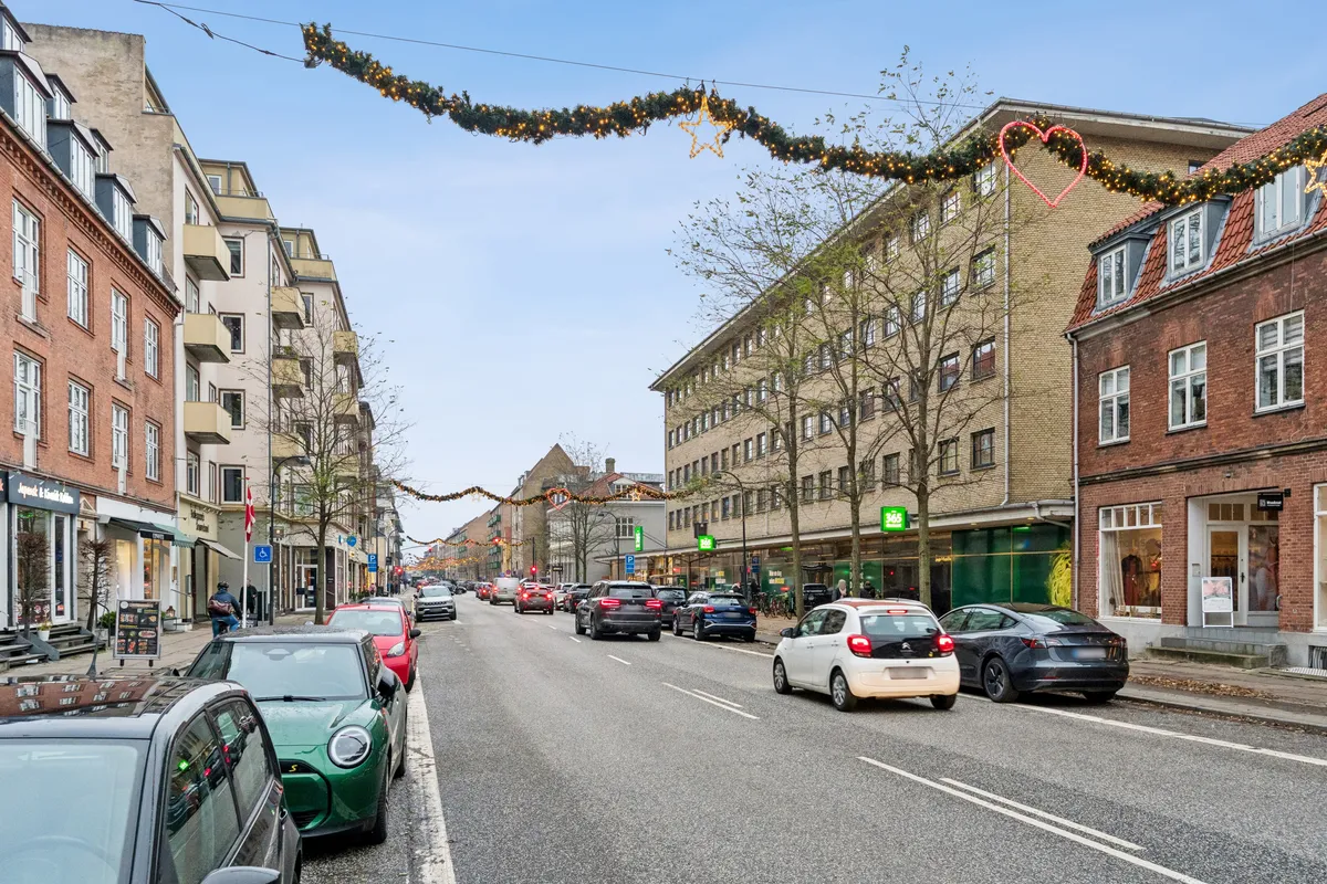 Mange biler parkeret langs Ordrupvej med grønne biler og en hvid bil foran og en sort bil bagved