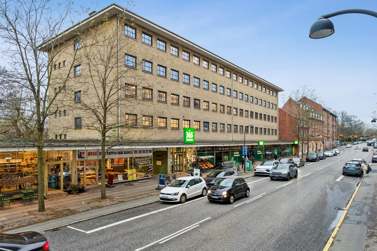 Kontor til leje på Ordrupvej 101, Charlottenlund. Vejen med biler og busser. Store vinduer og skrift. Busser og biler kører på vejen.