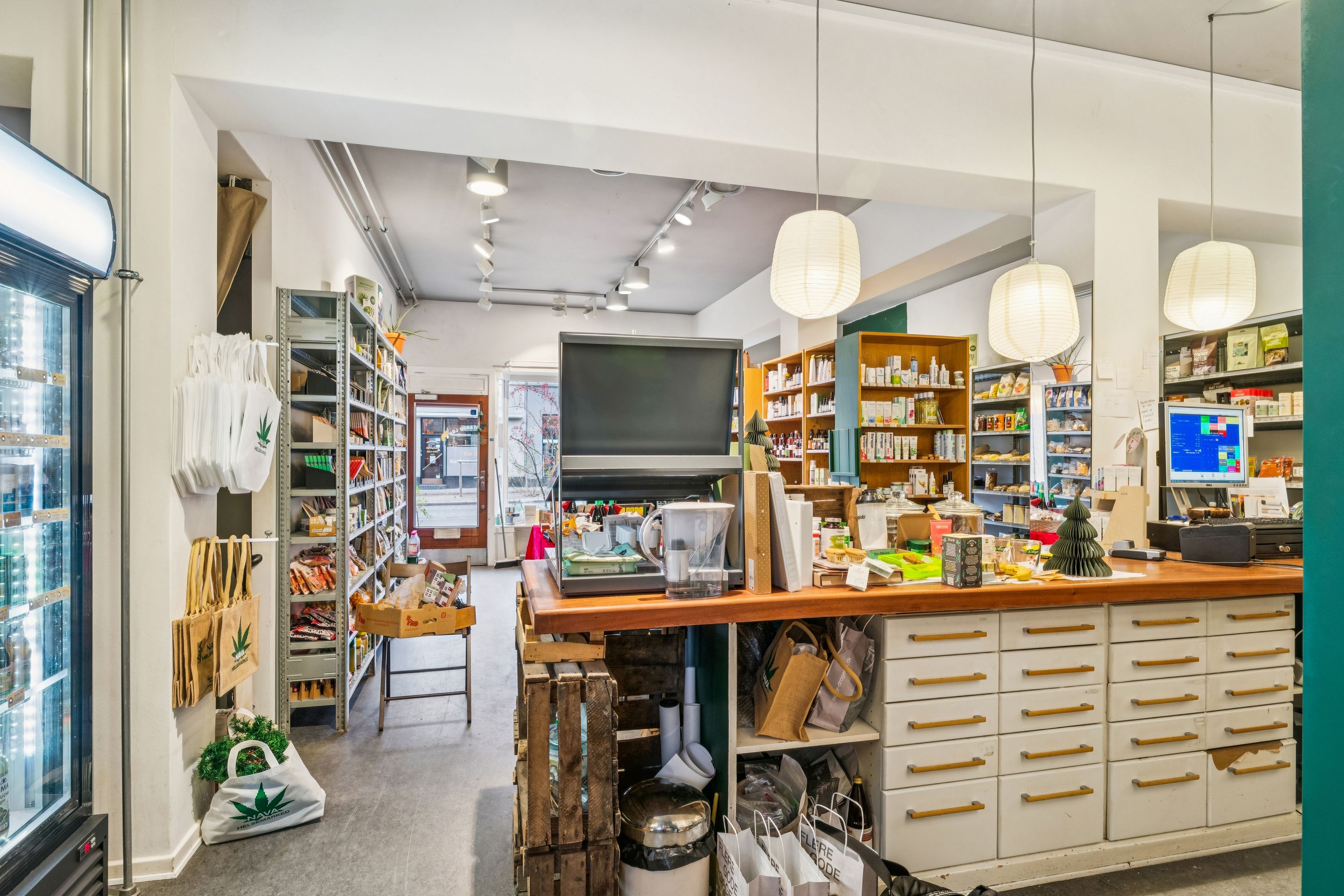 Interiøret i en køkkenudstyrsbutik med højt loft, lysekroner, skuffer, trækasser og en fryser. Butikken har et udvalg af køkkenprodukter og husholdningsartikler.