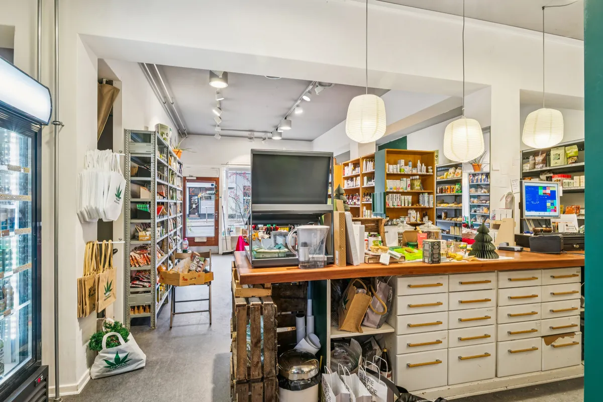 Interiøret i en køkkenudstyrsbutik med højt loft, lysekroner, skuffer, trækasser og en fryser. Butikken har et udvalg af køkkenprodukter og husholdningsartikler.