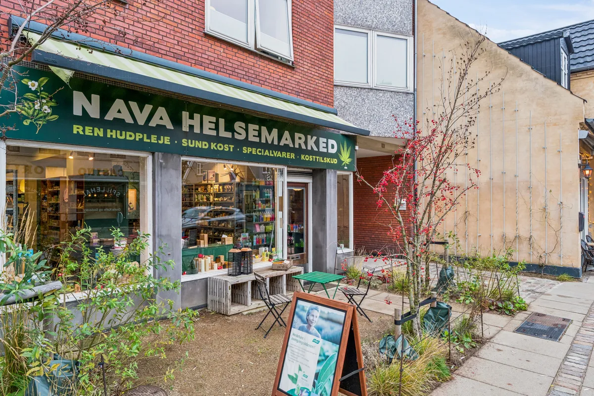En lille helsemarked med navnet Nava Helsemesteret ligger på Søborg Hovedgade. Butikken har et grønt banner med teksten Ren Hudpleje og Sund Kost. Der er grønne stole og bord foran butikken.