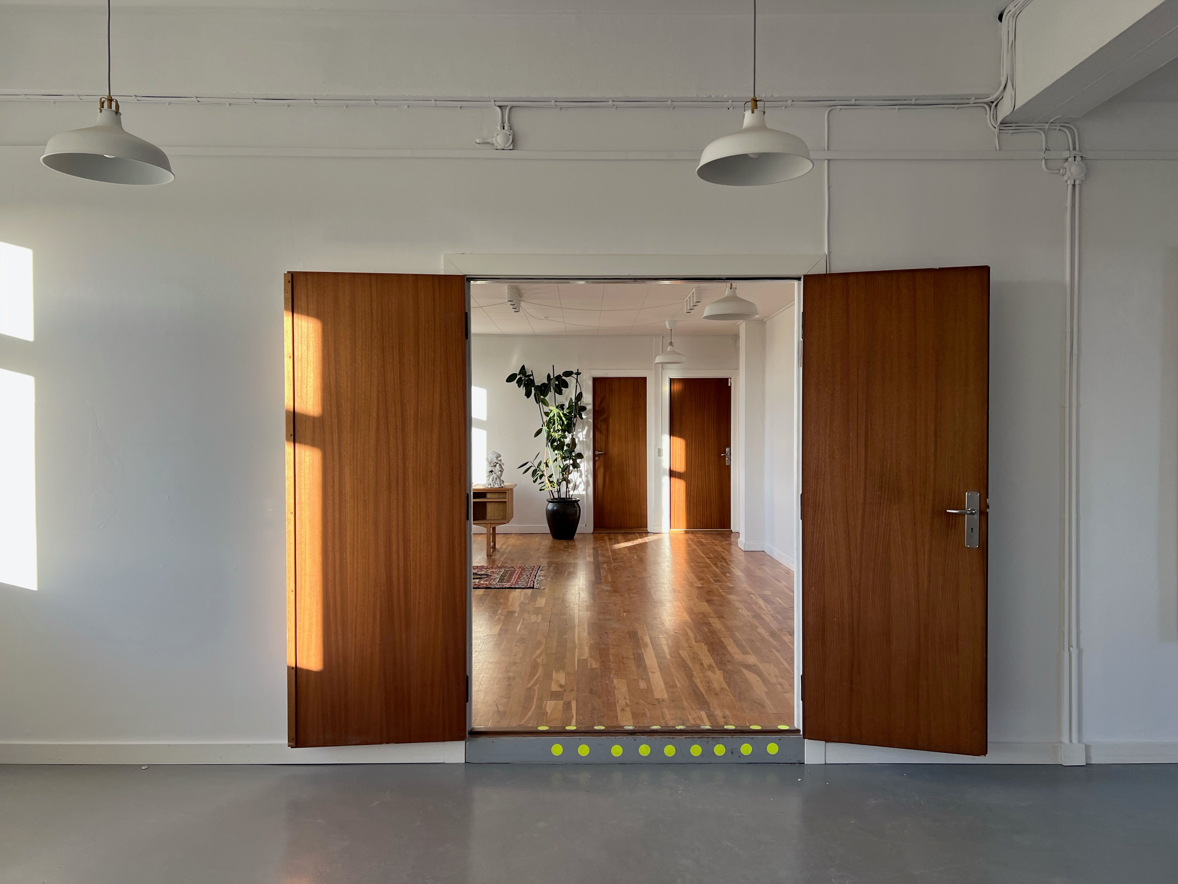 Store åbne døre med møbler og indretning i det elegante kontor med lyse gulve og hvide vægge