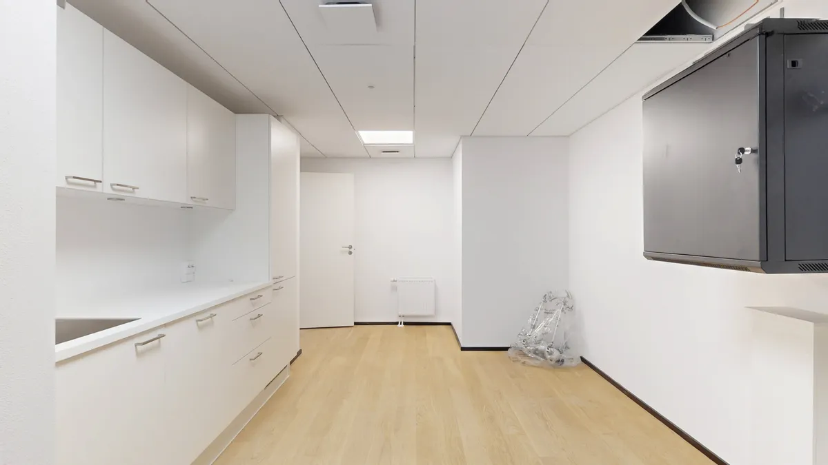 Ny Carlsberg Vej 42 er et fremlejemål med moderne køkken, hvidt loft og trægulv. Et værelse med hvide vægge og hvide kabinetter. Et kabinet med træhåndtag og stakkelser.