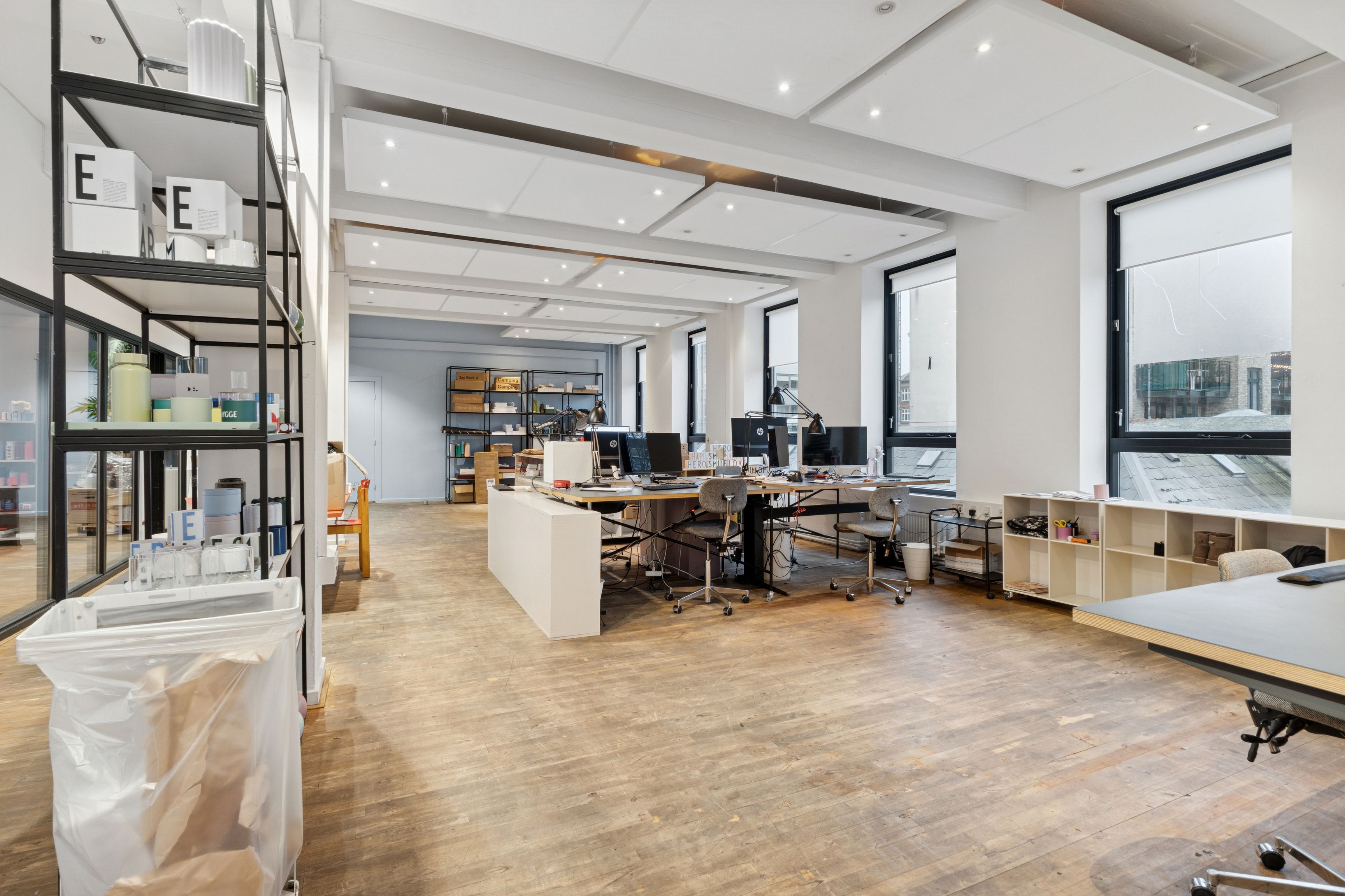 Storrumskontor med moderne indretning, trægulve, højt loft og vinduer med udsigt til byen