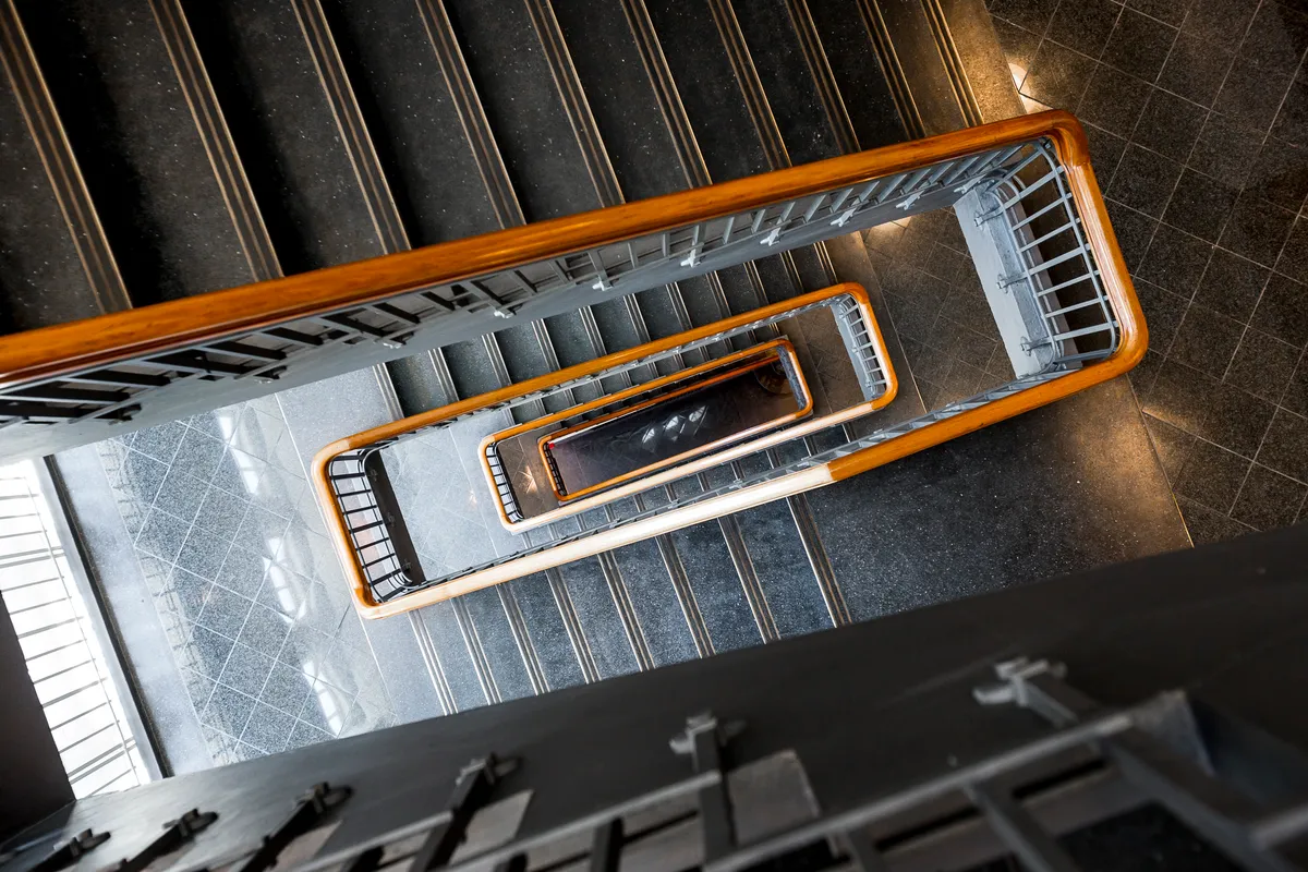 Se skrala i lysegult træ og sølvfarvet metal forbinder gulve med forskellige etager i en moderne kontorbygning med lys refleksion på gulvet