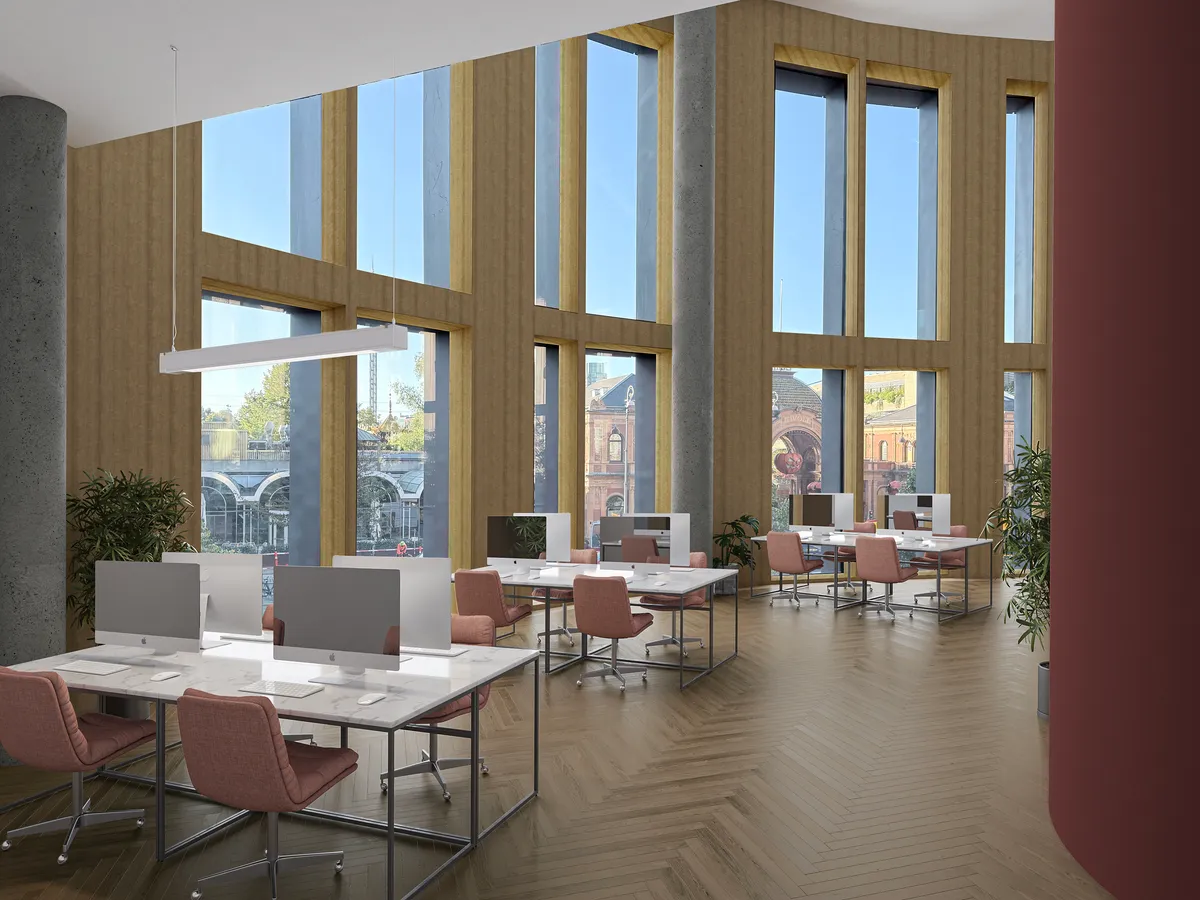 Et moderne kontor med store vinduer og 6 meter højt loft, med smuk udsigt og masser af lys. Kontoret er udstyret med højkvalitetsborde, lyserøde stole og computere.