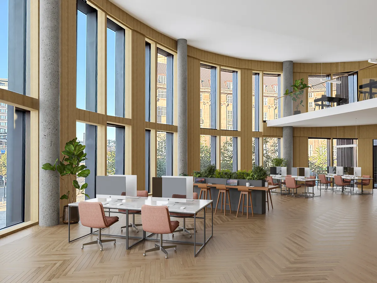 Stort kontor med højt loft, lyse vinduer og masser af plantevækst. De mange borde og stole er arrangeret rundt om kontoret. Lysindfaldet og udsigten til Tivoli er enestående.