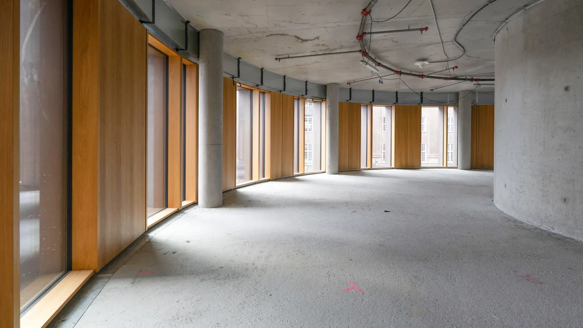 Lys ind ad glasruder i store lokaler med højt loft og træbeklædning. Lysindfald med udsigt til Tivoli og andre bygninger.