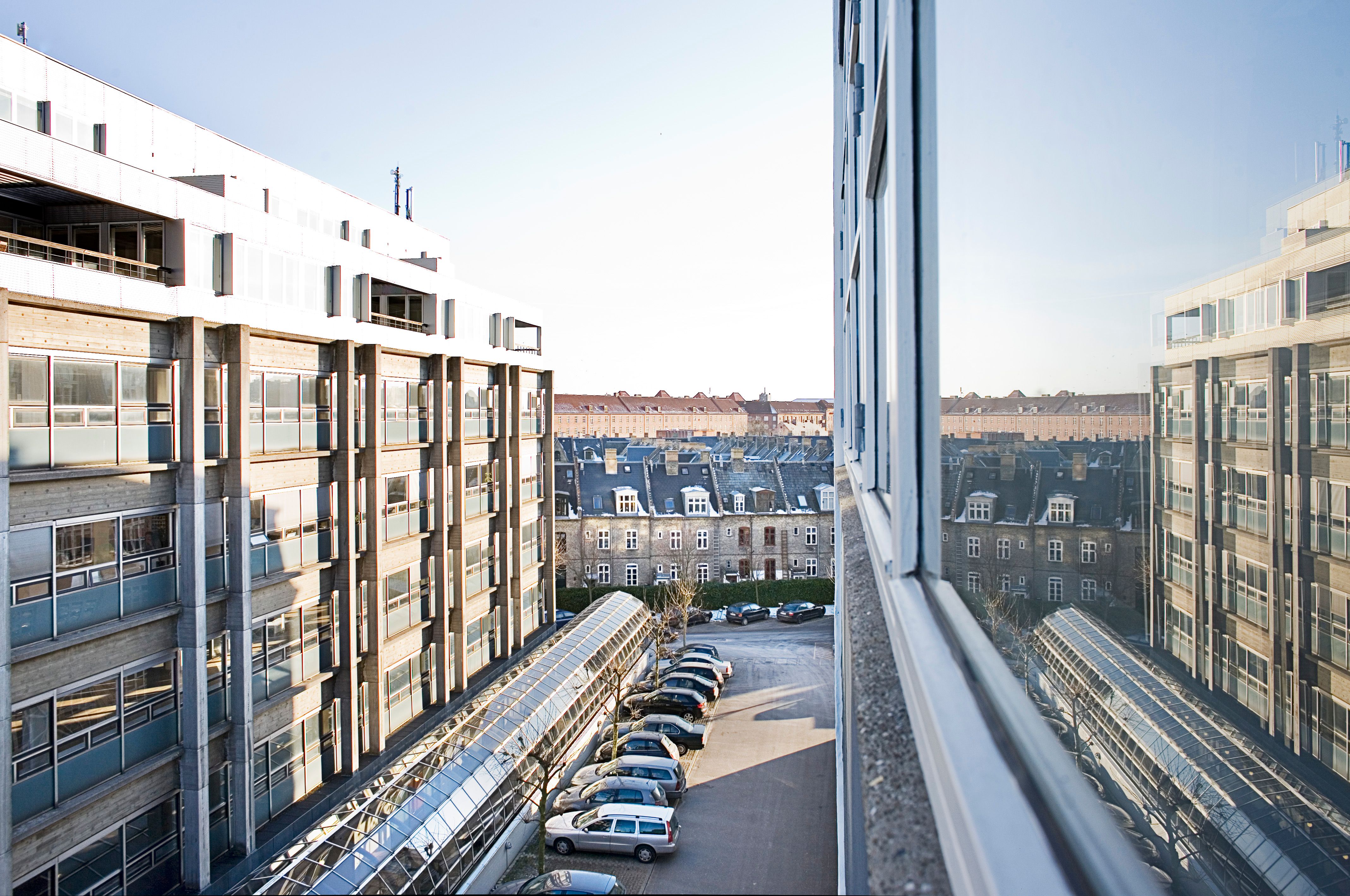 Højloftet lejemål med karakter i B!NGS kontorhus på Vesterbro. Mange parkerede biler og smukke bygninger i baggrunden