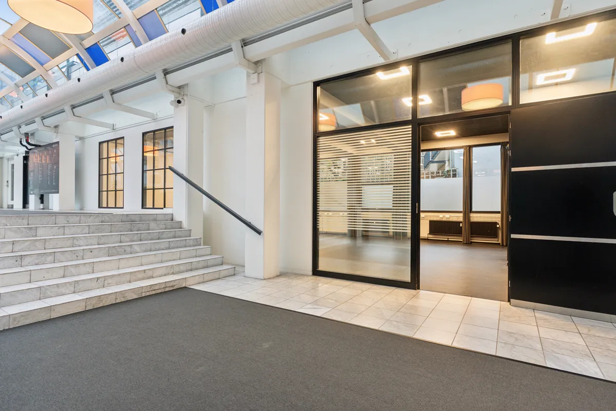 Indvendigt højloftet kontorhus med lyse glasdøre og terrasse, luksuriøs marmortrappe og slanke stålhåndtag. Moderne interiør med lyse loftsvinduer og slanke glasruder.