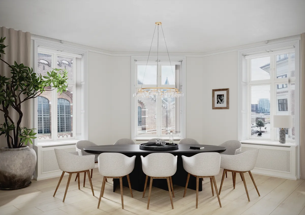 En moderne, hvidt dekoreret kontor med rundt bord og høje vinduer i hjertet af København. Rundt gulvlampe, plante og lysestole. Billeder og lampe på vindueskarme.