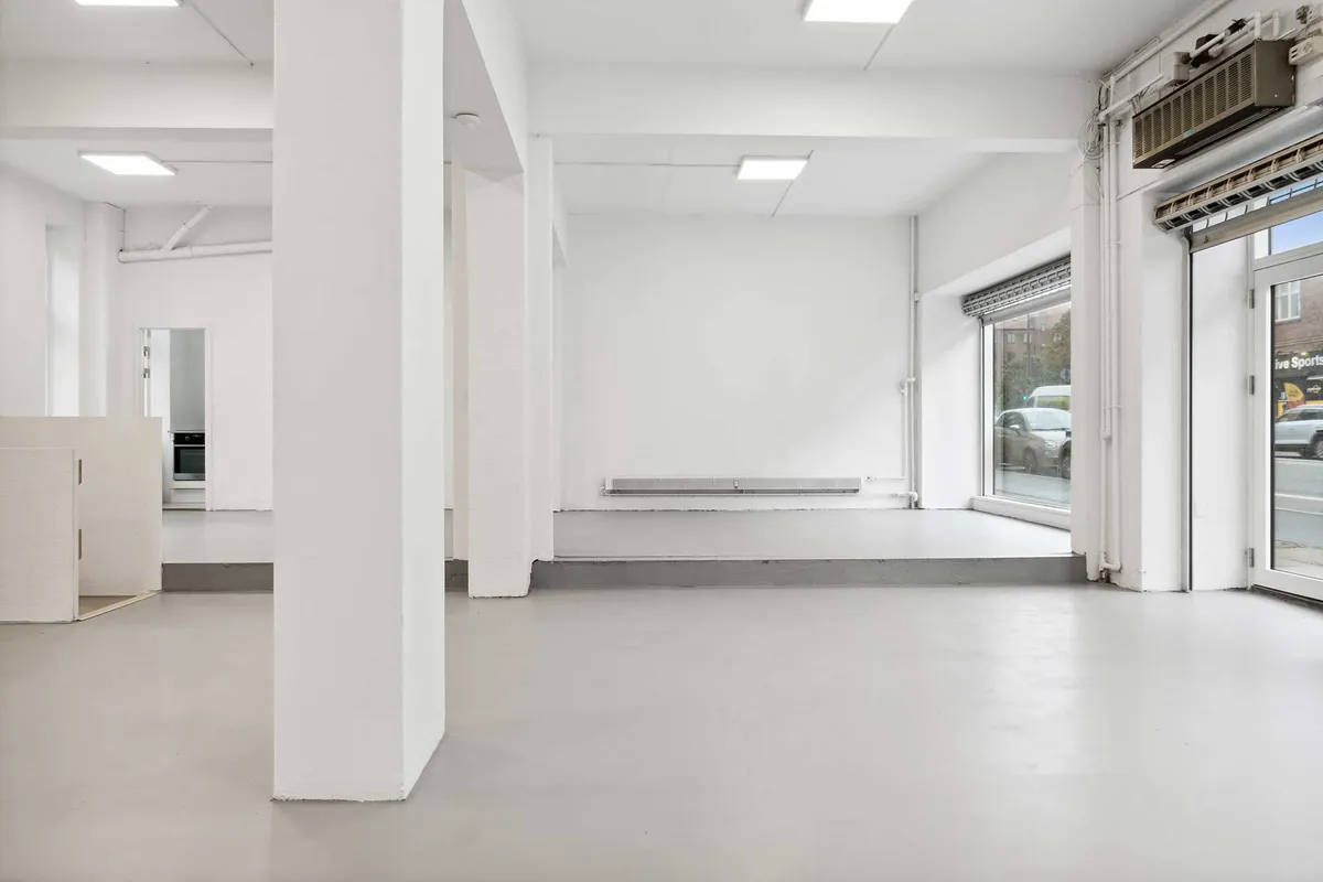 Foto af en stor butik med hvide vægge og gulv samt stående søjler, der står tomme og venter på en ny lejer
