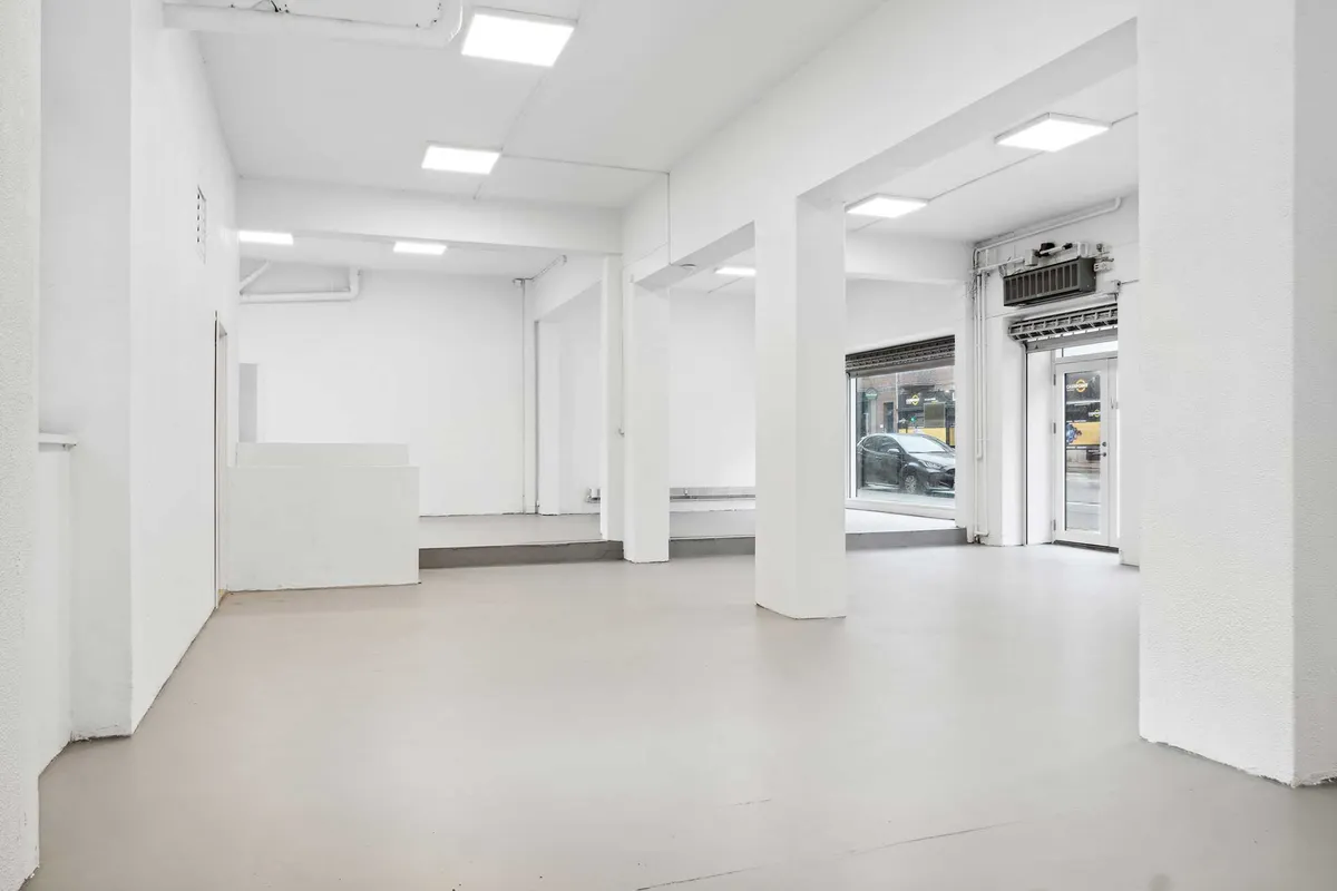 Hvid og neutral indretning med lysekroner, glasdøre og høje hvide vægge i en tom butik til leje på Toftegårds Allé 42, 2500 Valby
