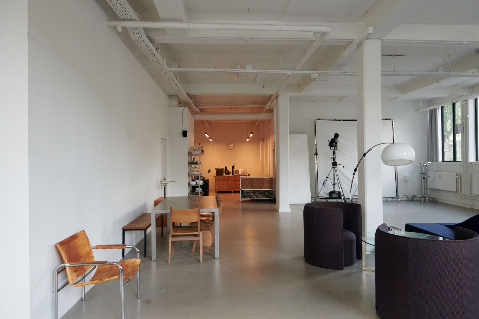 Kontorlejemål med moderne møbler og faciliteter i Nordvest. Værelse med borde, stole, sofaer og lamper. Væggene er hvide og gulvet er lysegråt.