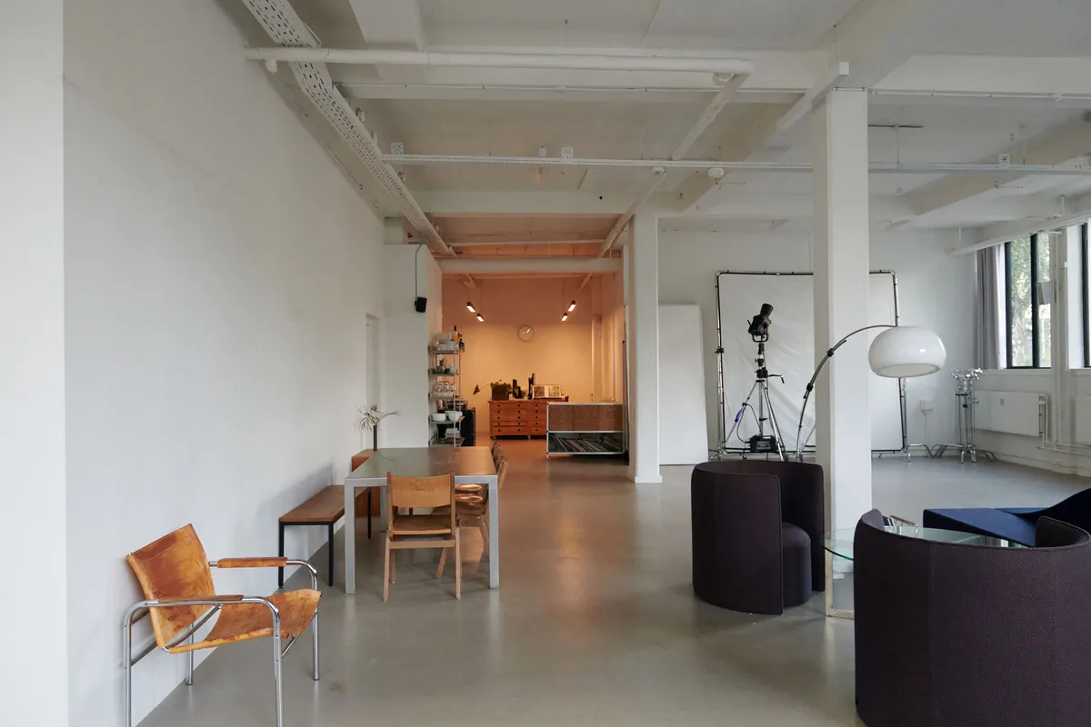 Kontorlejemål med moderne møbler og faciliteter i Nordvest. Værelse med borde, stole, sofaer og lamper. Væggene er hvide og gulvet er lysegråt.