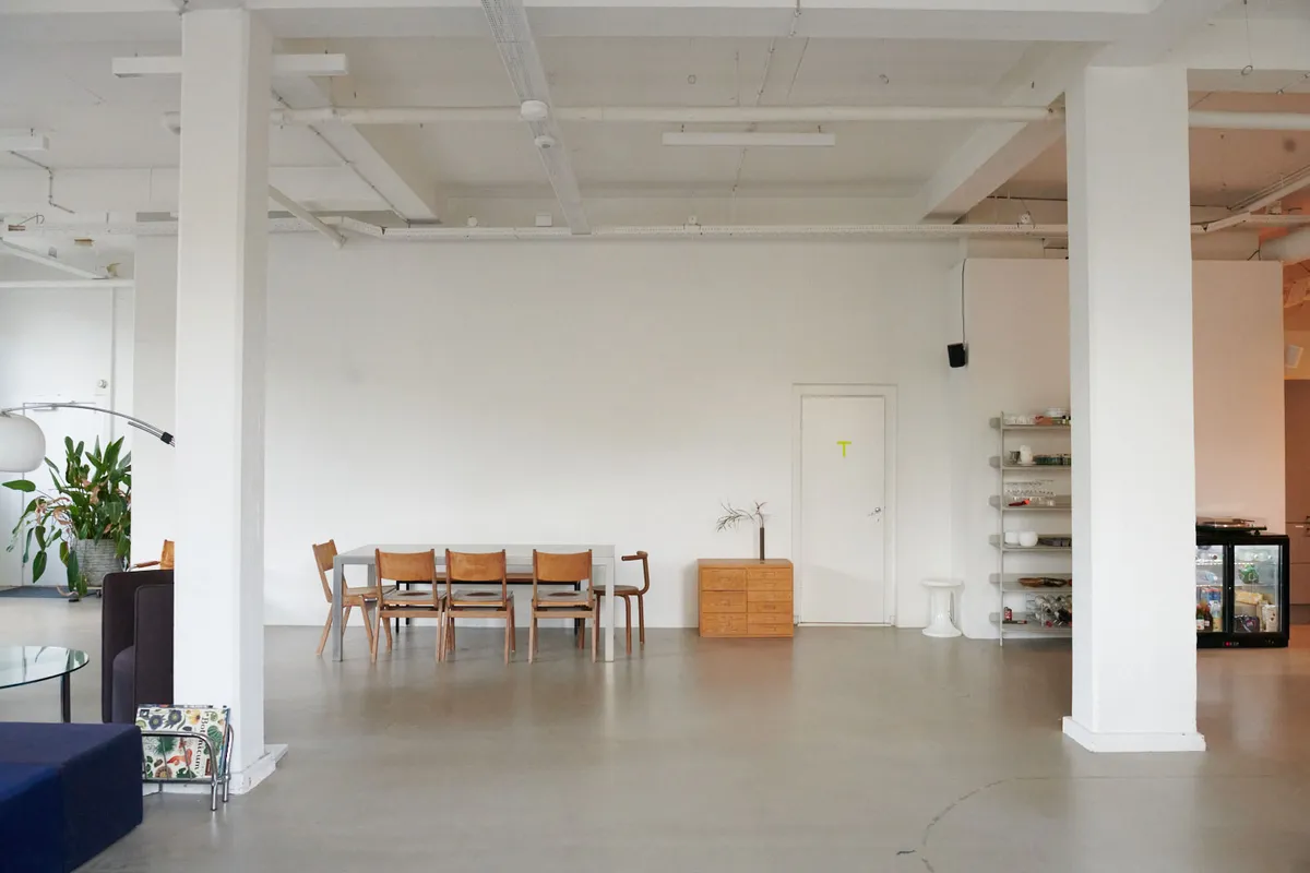 Kontorlejemål med møbel og indretning i København NV, med træbord og stole, en lampe, plante og en køleskab i hvid farve