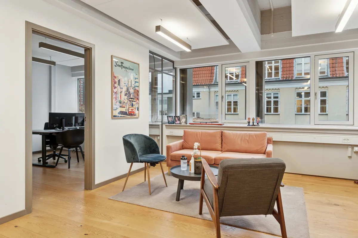 Lækkert istandsat kontorlejemål med ventilation, lysevinduer og tekstiler i lyst og lyst gulv og kontormøbler med et billede på væggen