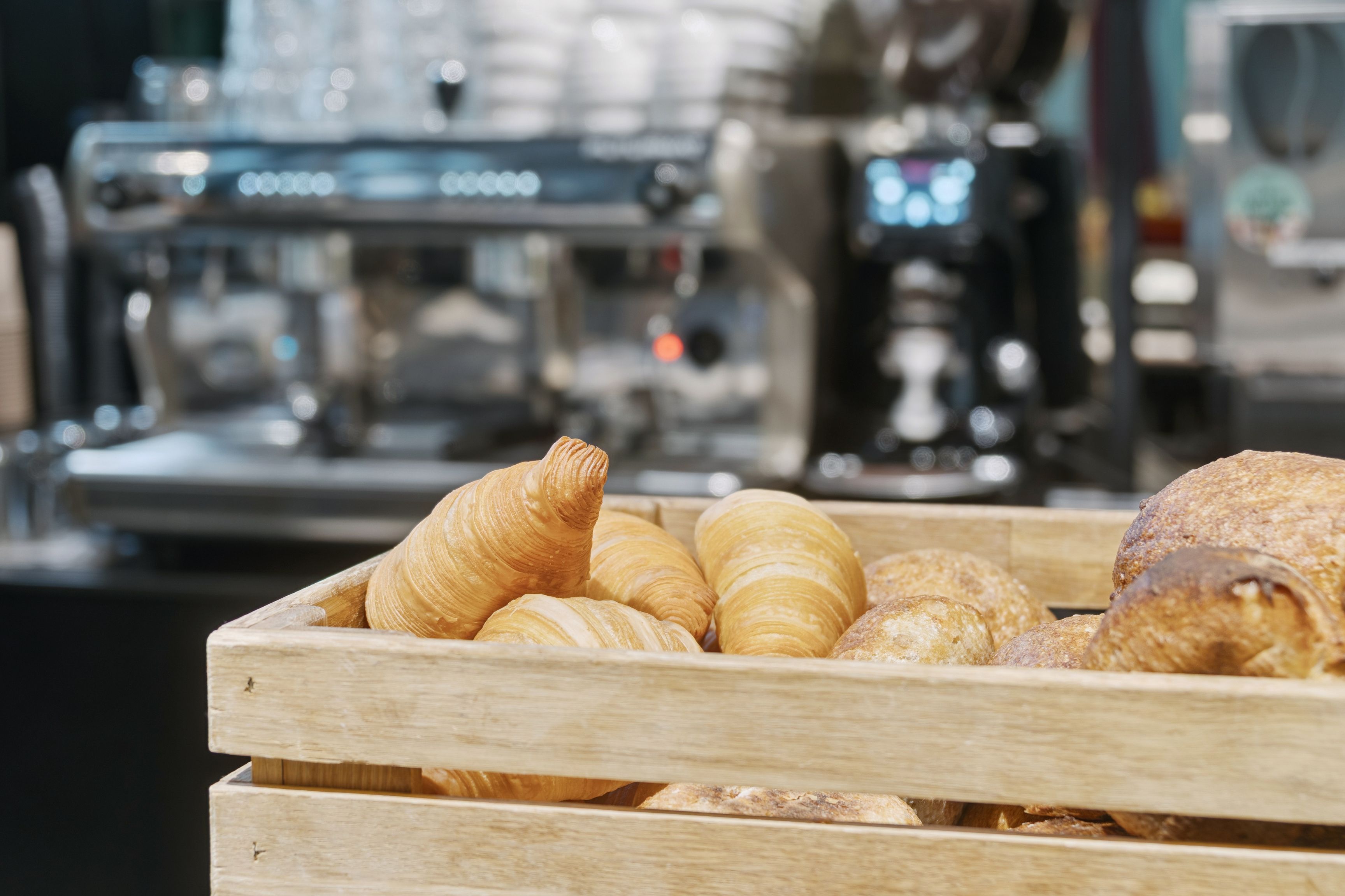 Lækkert krusmølle og croissanter i trækasse med bageri i baggrunden
