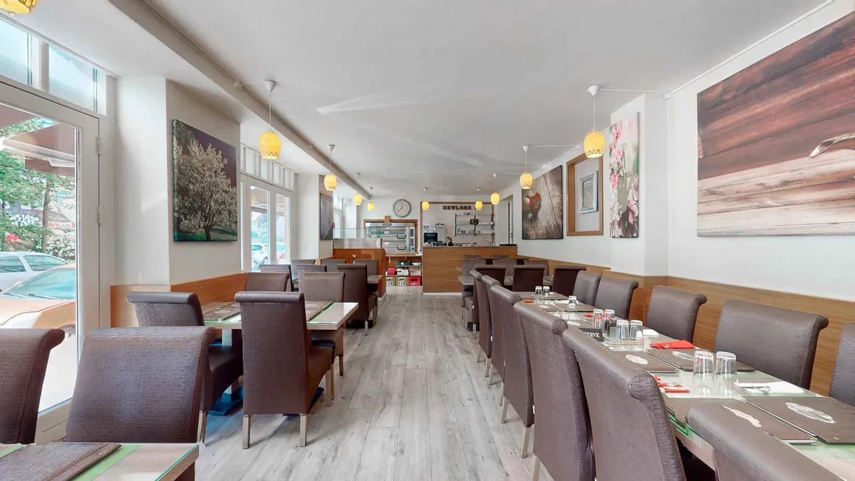 Lys moderne restaurant med lysekroner, borde og stole og udsigt til park og biler på Jagtvej 119, 2200 København N