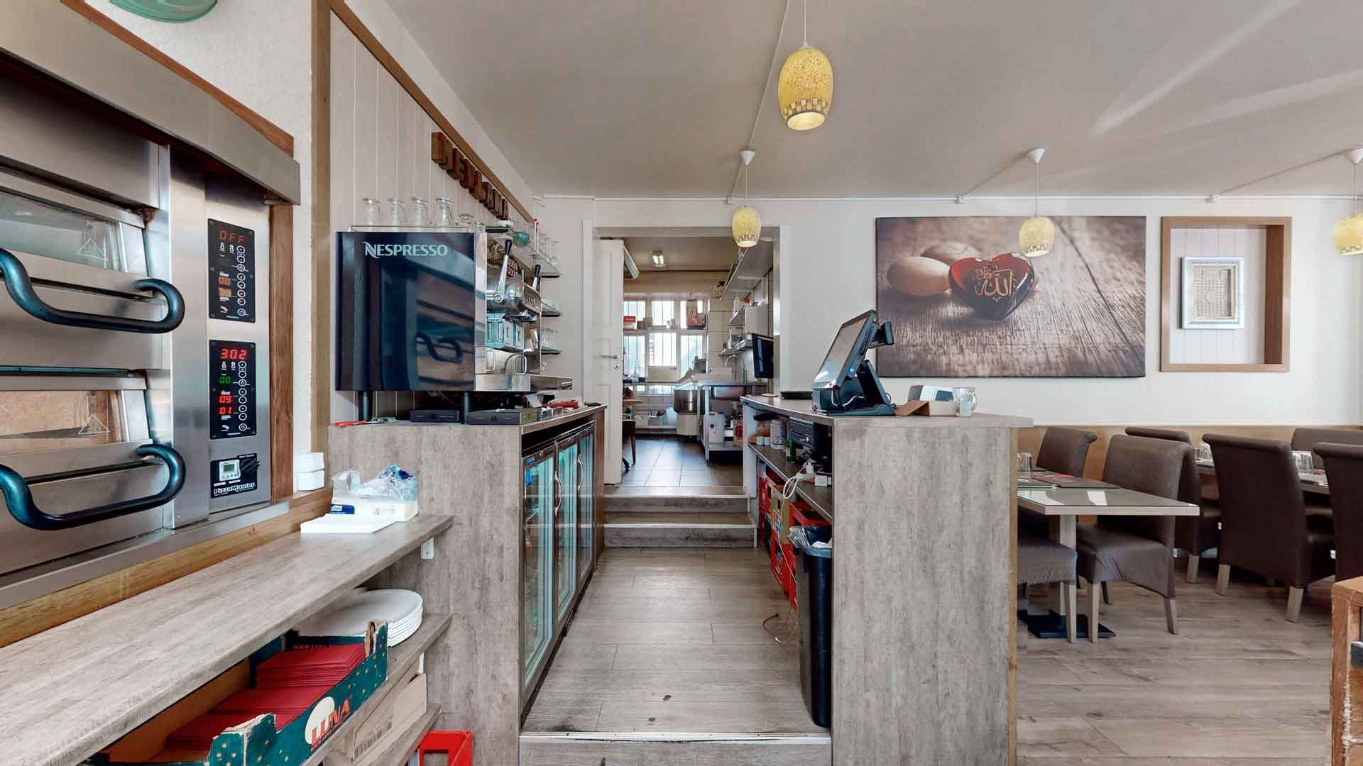 En ren og veludstyret køkkenafdeling i en restaurant med smukke møbler og en Nespresso-maskine samt en stor maleri på væggen