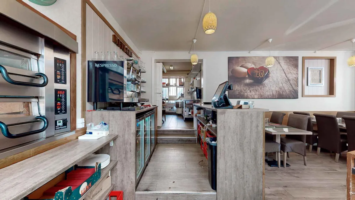 En ren og veludstyret køkkenafdeling i en restaurant med smukke møbler og en Nespresso-maskine samt en stor maleri på væggen