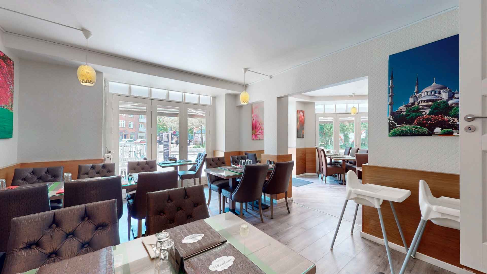 Lys moderne restaurant med lyse trægulve og røde læderstole samt lyse loftslamper og smukt maleri med Istanbuls skyline bagved bordene