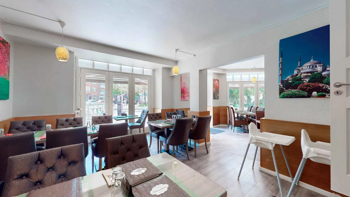 Lys moderne restaurant med lyse trægulve og røde læderstole samt lyse loftslamper og smukt maleri med Istanbuls skyline bagved bordene